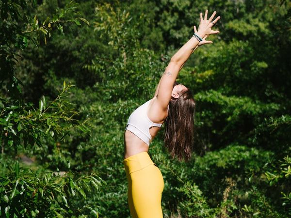 Woman meditating peacefully with a green forest background.